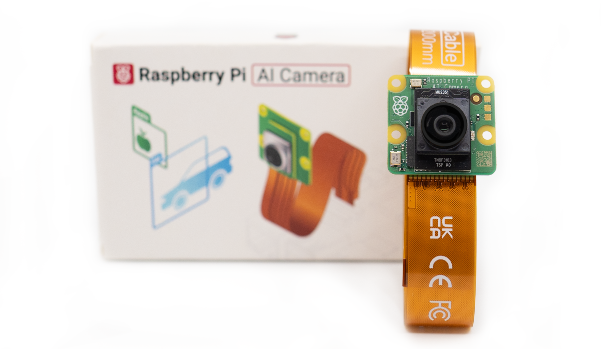 A photograph of the Raspberry Pi AI Camera accessory in front of its commercial packaging box